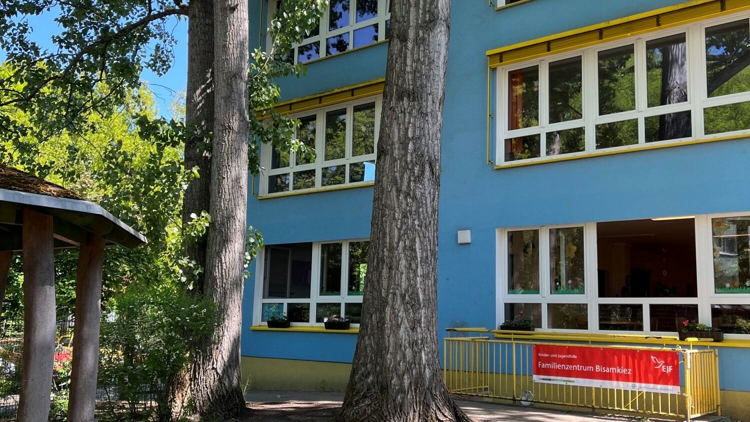 Teil eines blauen Gebäudes mit Bäumen im Vordergrund